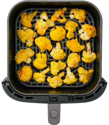A top view of an air fryer basket filled with golden, roasted cauliflower florets.