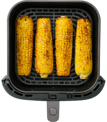 Four grilled corn cobs are arranged in an air fryer basket, showcasing a golden-brown, charred appearance.