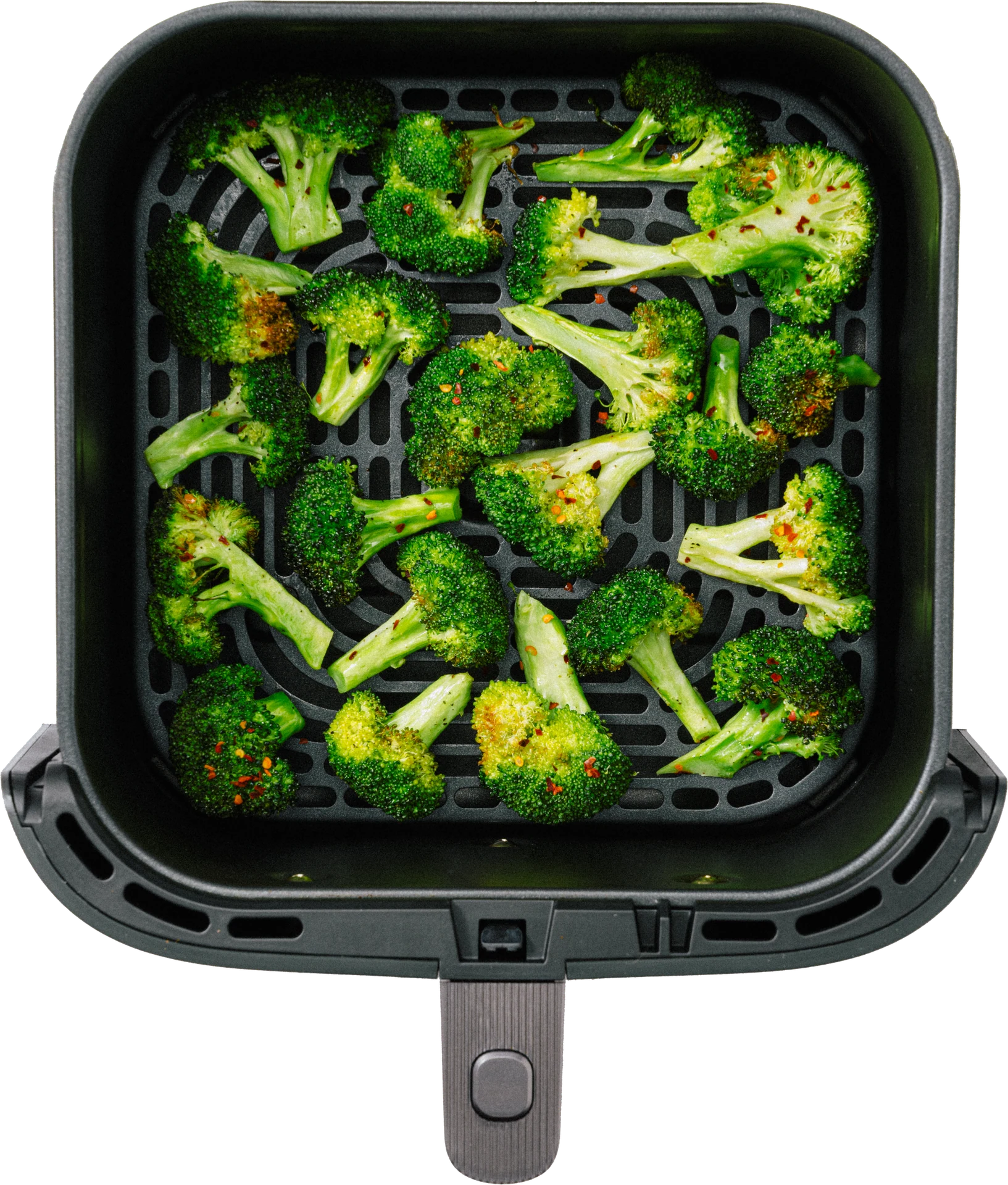 A black air fryer basket filled with vibrant green broccoli florets, some sprinkled with red seasoning.