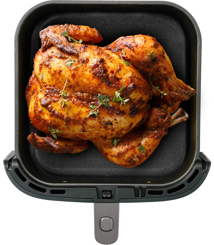 A perfectly roasted chicken garnished with herbs, placed in a black cooking tray.